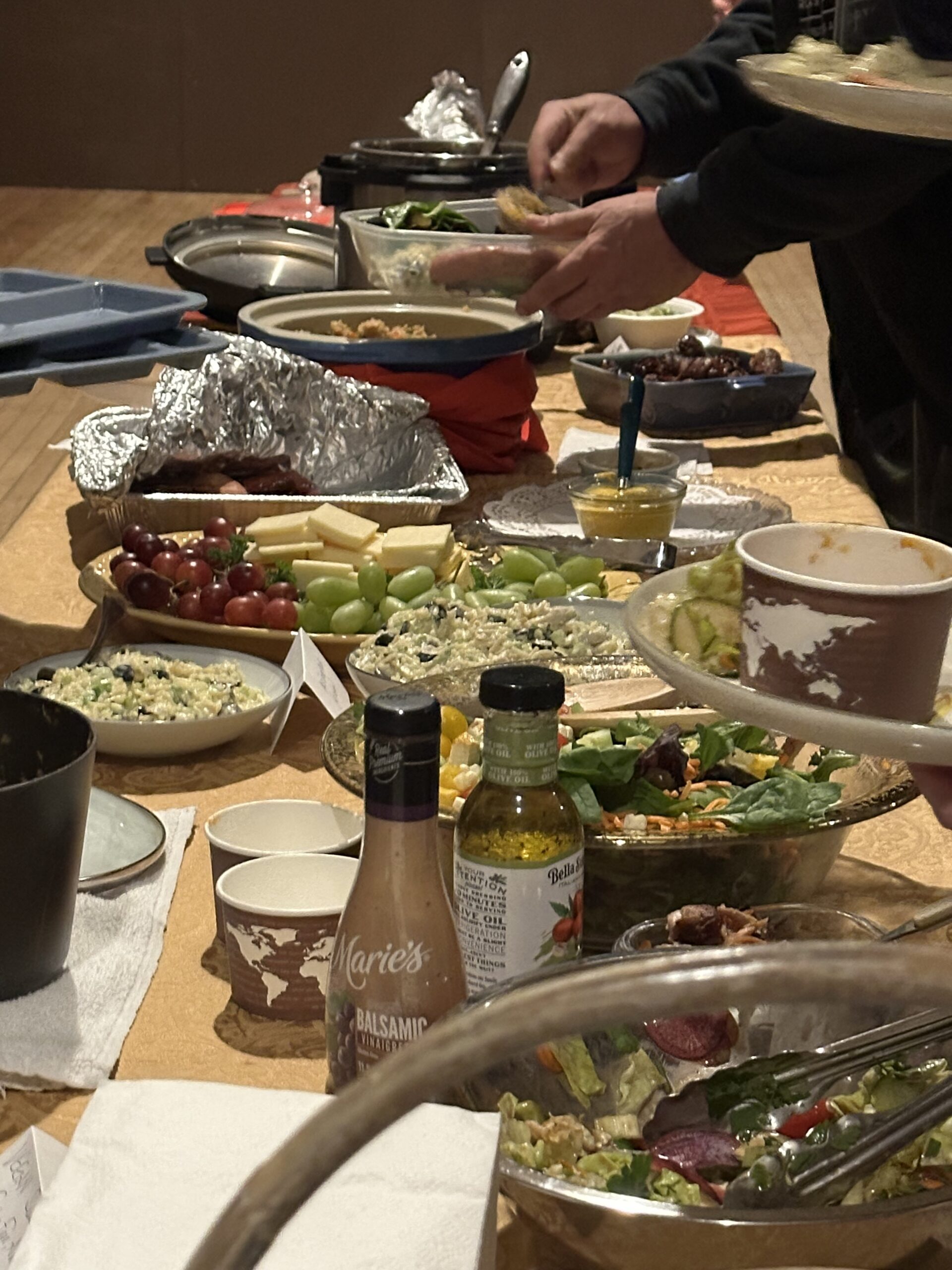 Image depicts table laden with a variety of food laid out buffet style